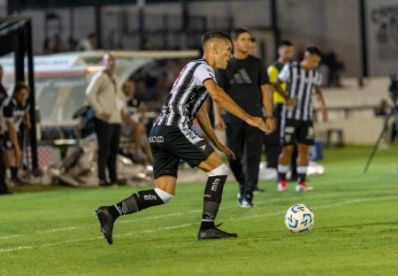 Soccer player dribbling ball during a match on a well-lit stadium field.