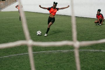 Women soccer players practicing on a green field, displaying teamwork and active participation.