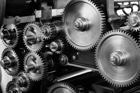 Close-up view of a complex industrial gear mechanism in black and white.