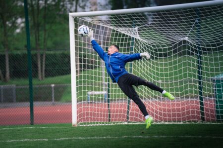 Dynamic shot of a goalkeeper saving a soccer ball during a match in Rennes, France.
