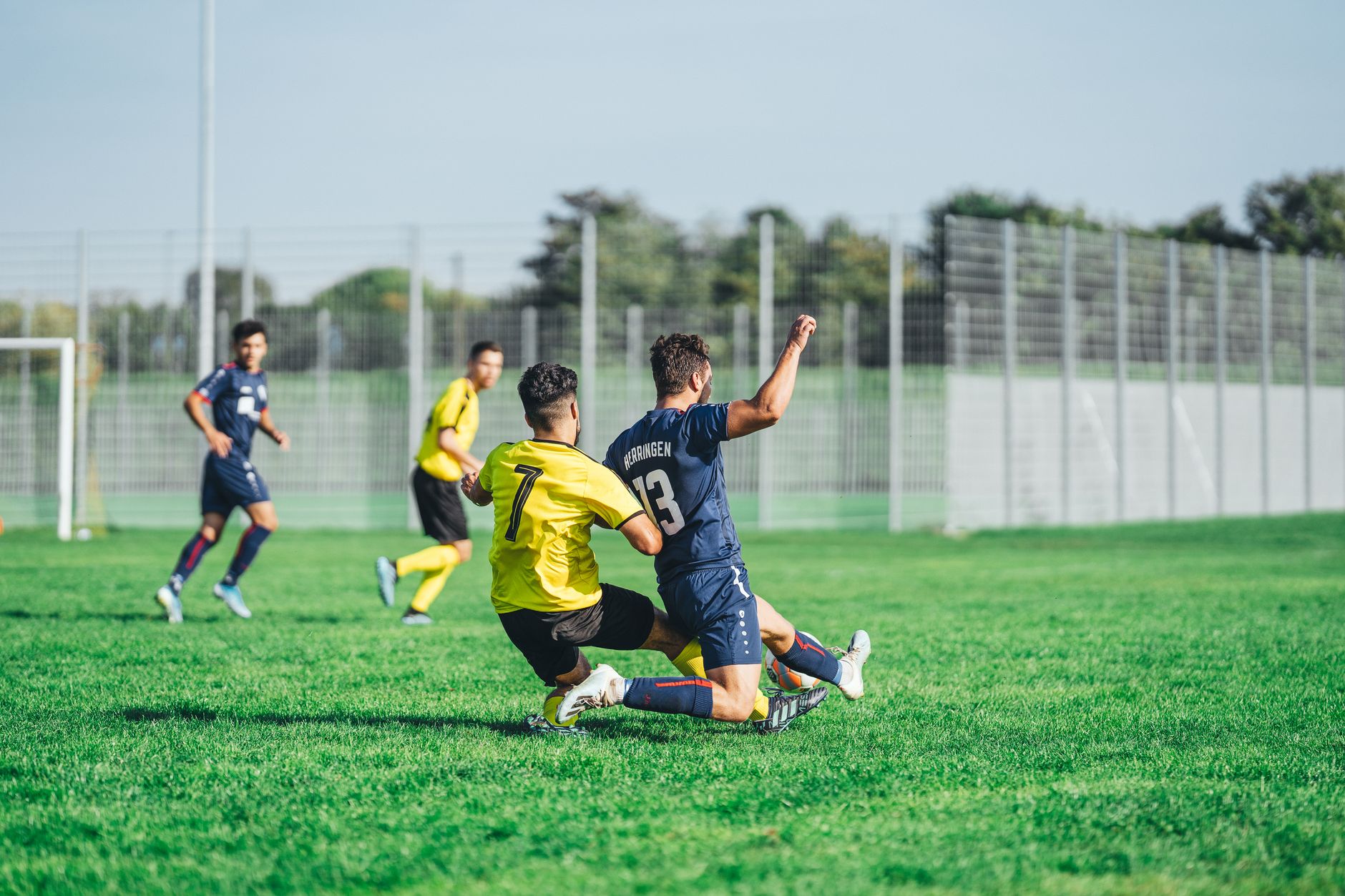 Deux joueurs de football disputant le ballon au cours d’un match sur une pelouse extérieure.