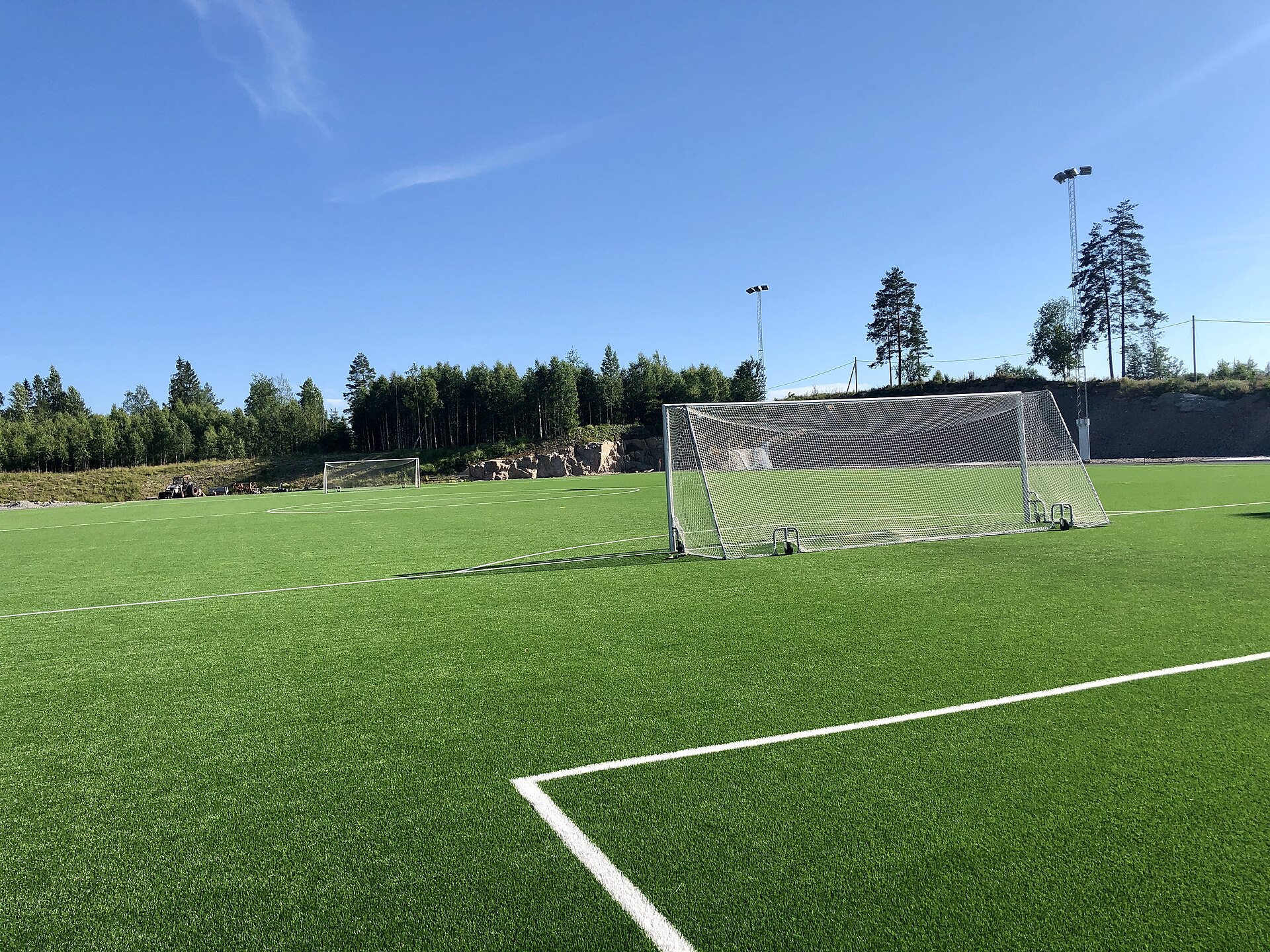 Terrain de football synthétique et but sous un ciel bleu